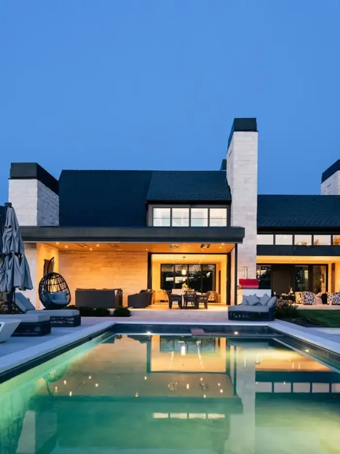 Custom home exterior at dusk with stone entry, dormers and landscaped drive