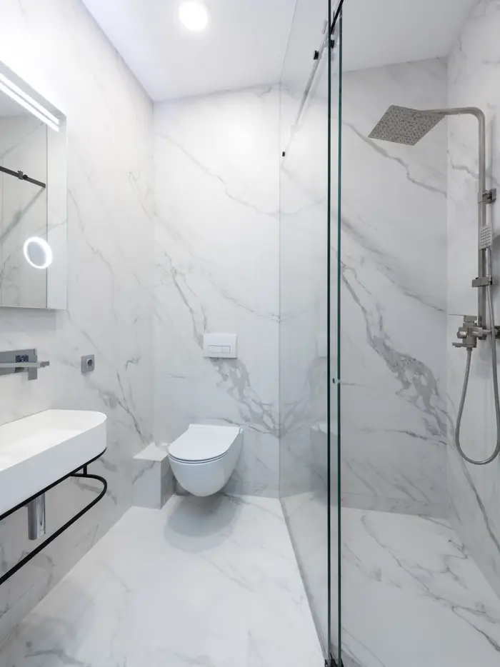 Marble-clad walk-in shower with rainfall head and glass panel